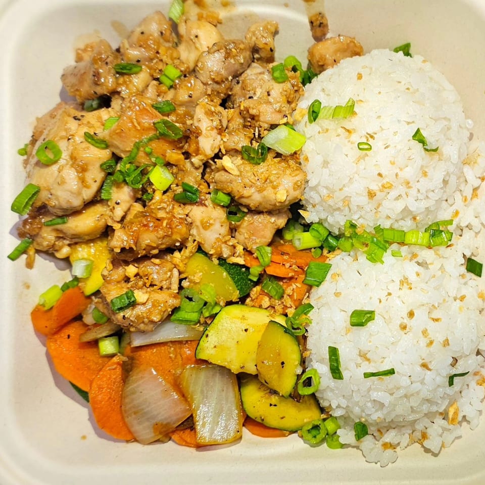 Truk N Yaki's garlic chicken with white rice, carrots, zucchini, and onions, garnished with scallions.