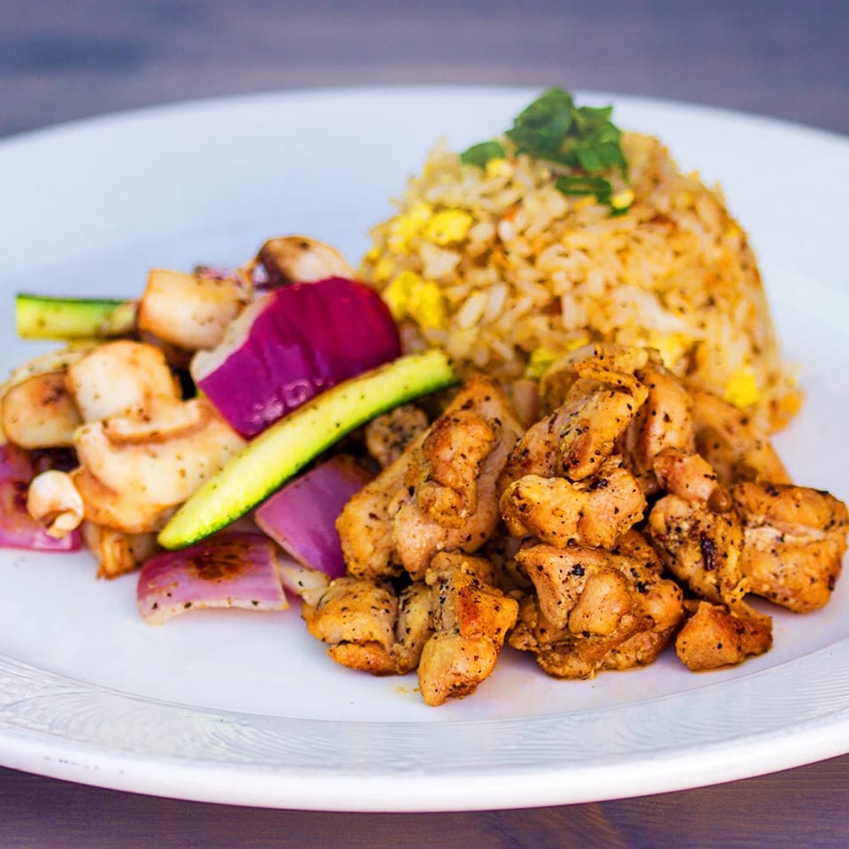 Truk N Yaki's chicken hibachi with fried rice, zucchini, mushrooms, and red onions on a white plate.