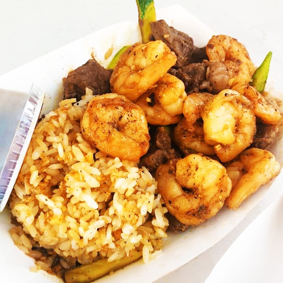 Truk N Yaki's shrimp and beef hibachi with fried rice and green vegetables in a white container.